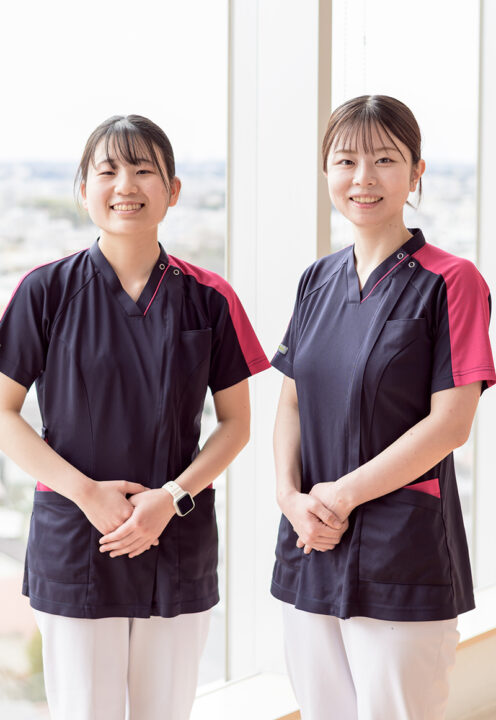 窓際に笑顔で立っている二人の看護師